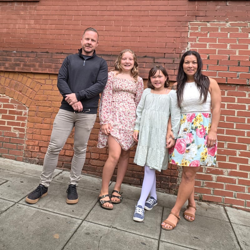 Tom and family standing by a brick wall